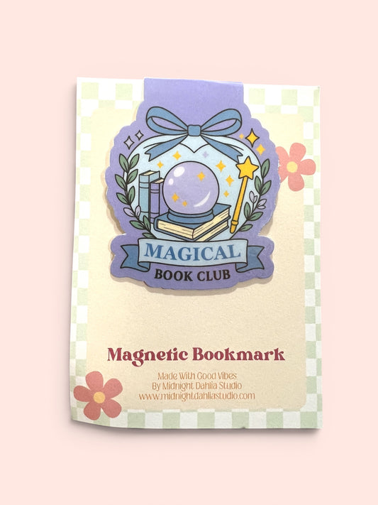 A decorative magnetic bookmark for a 'Magical Book Club' featuring a purple crystal ball, books, a wand, and stars, presented on a cream card with a green-and-white checkered border against a soft pink background.