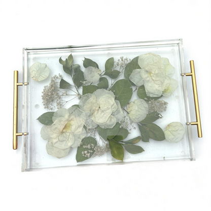 Decorative tray with pressed flowers and greenery on a white background
