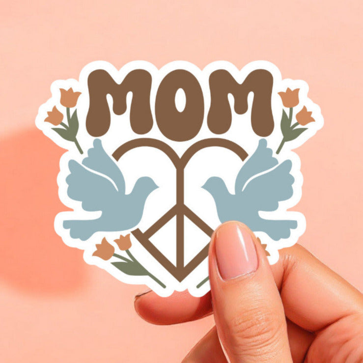 a sticker with the word mom with a heart shaped peace sign with a light blue dove on either side