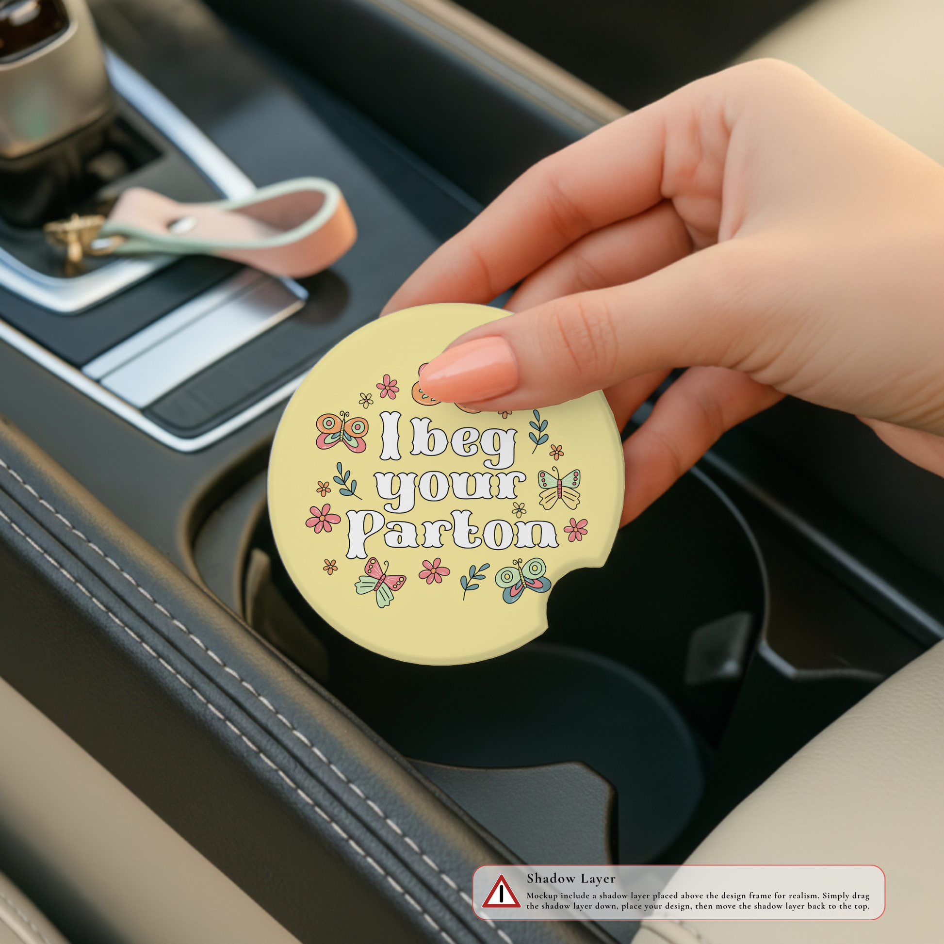 Hand holding a car coaster with humorous text design in a car's cup holder.