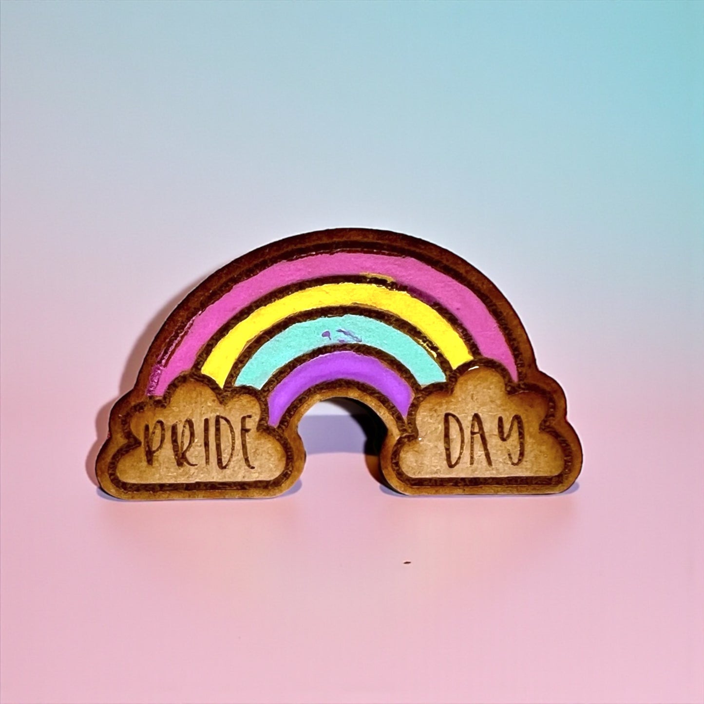 Rainbow-shaped wooden ornament with 'PRIDE DAY' on a gradient background