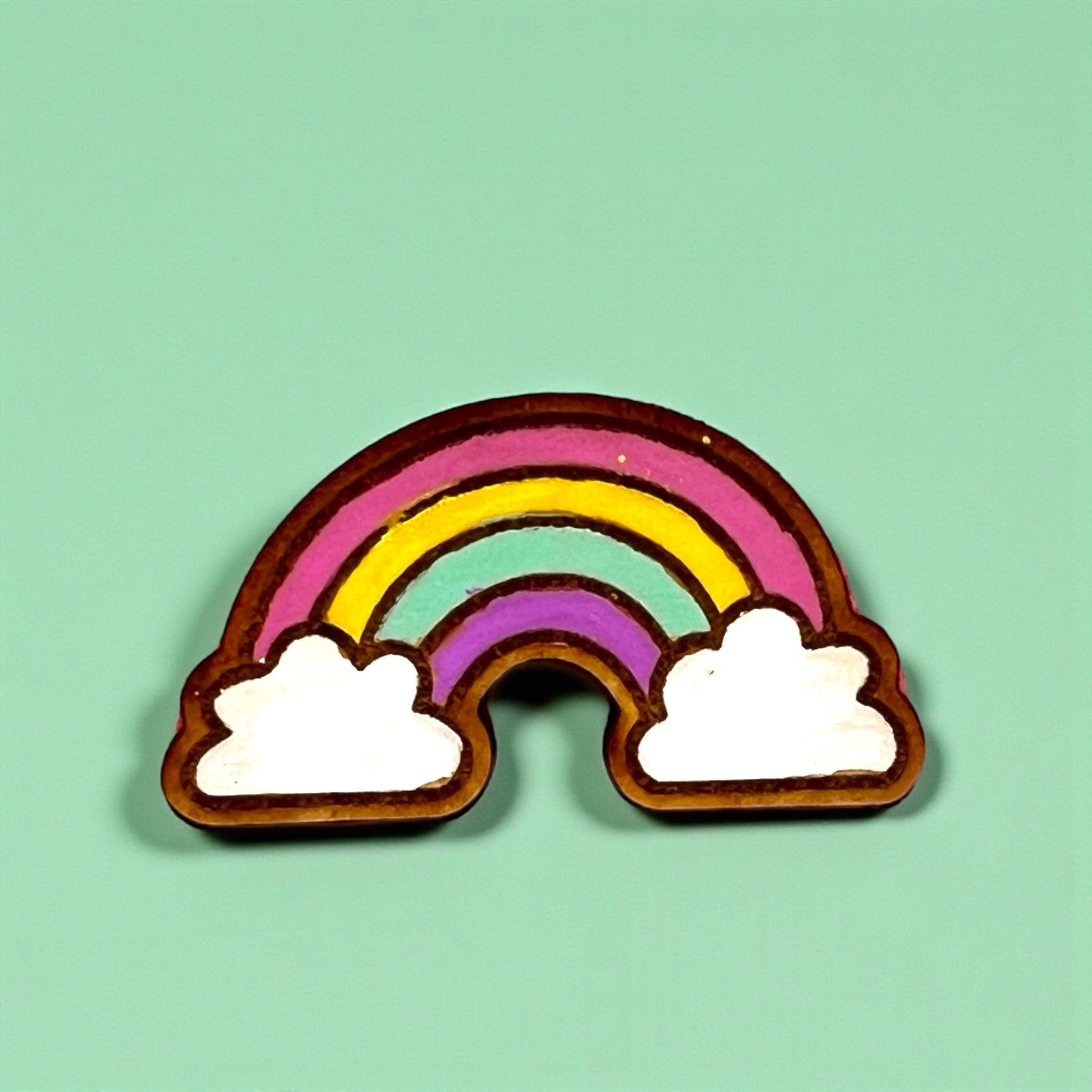 Rainbow-shaped cookie with white clouds on a light green background