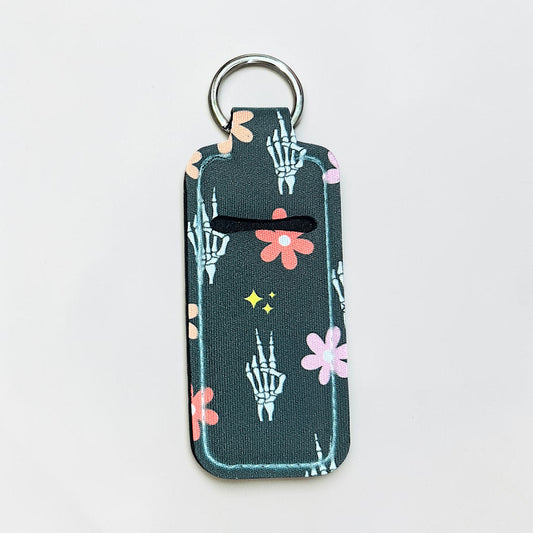 Keychain with skeleton hand and flower design on a gray background