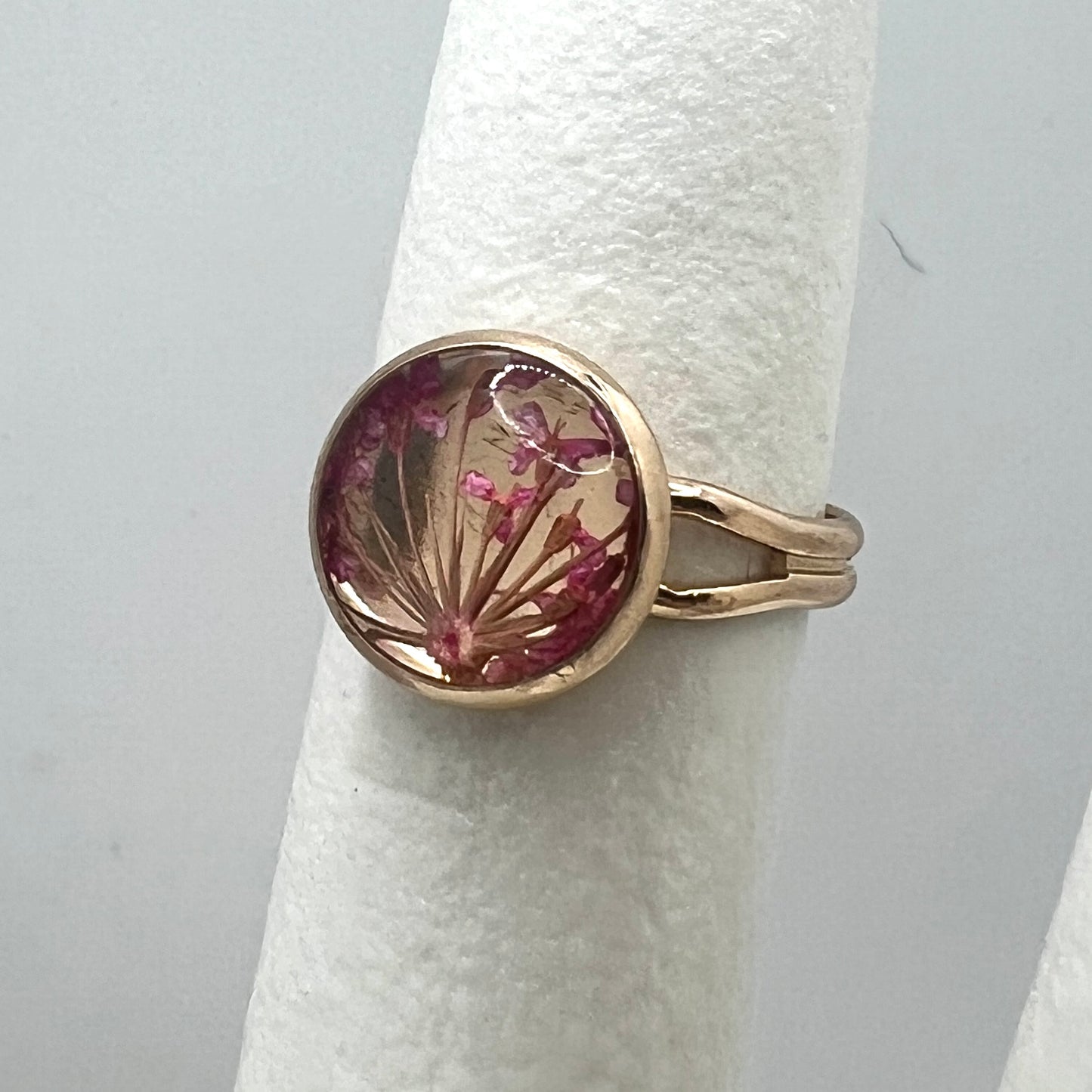 Gold ring with a circular design featuring pink flowers on a white background