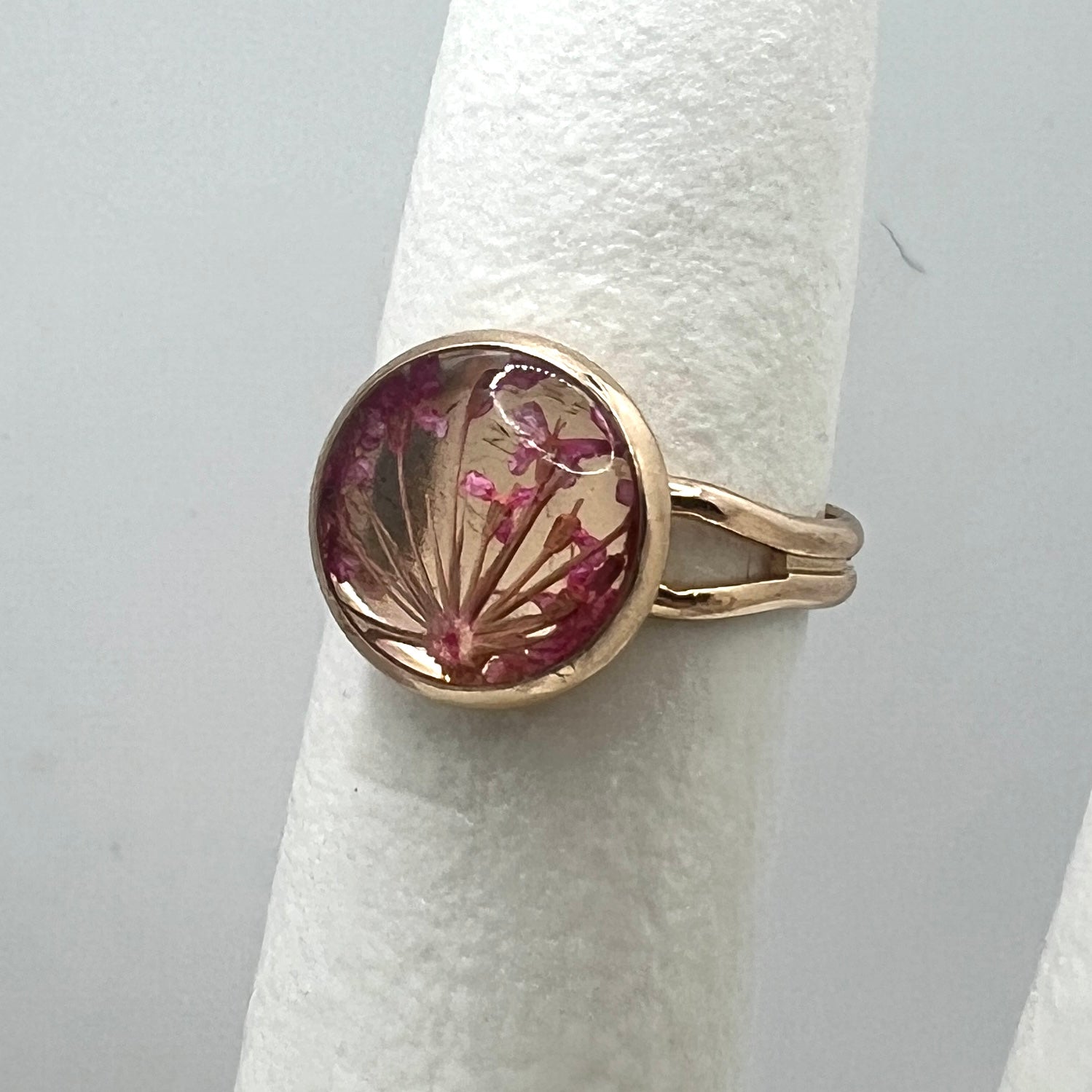 Gold ring with a circular design featuring pink flowers on a white background