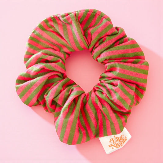 Red and green striped scrunchie with a brand label on a pink background