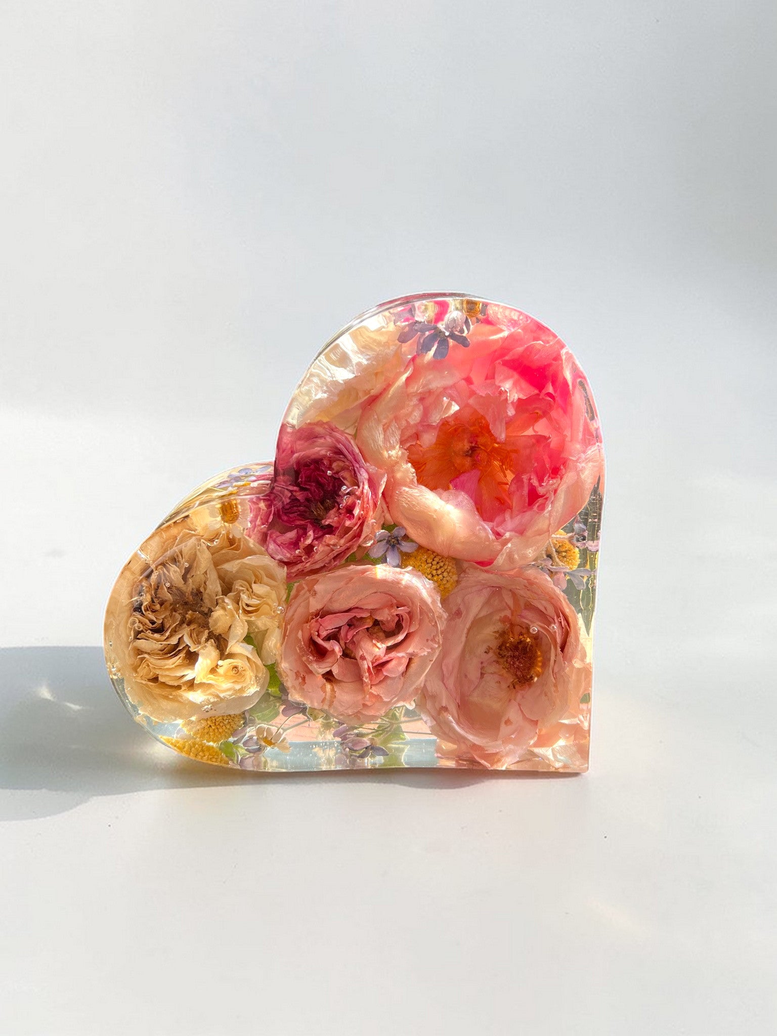 Heart-shaped resin piece with pink and yellow flowers on a white background