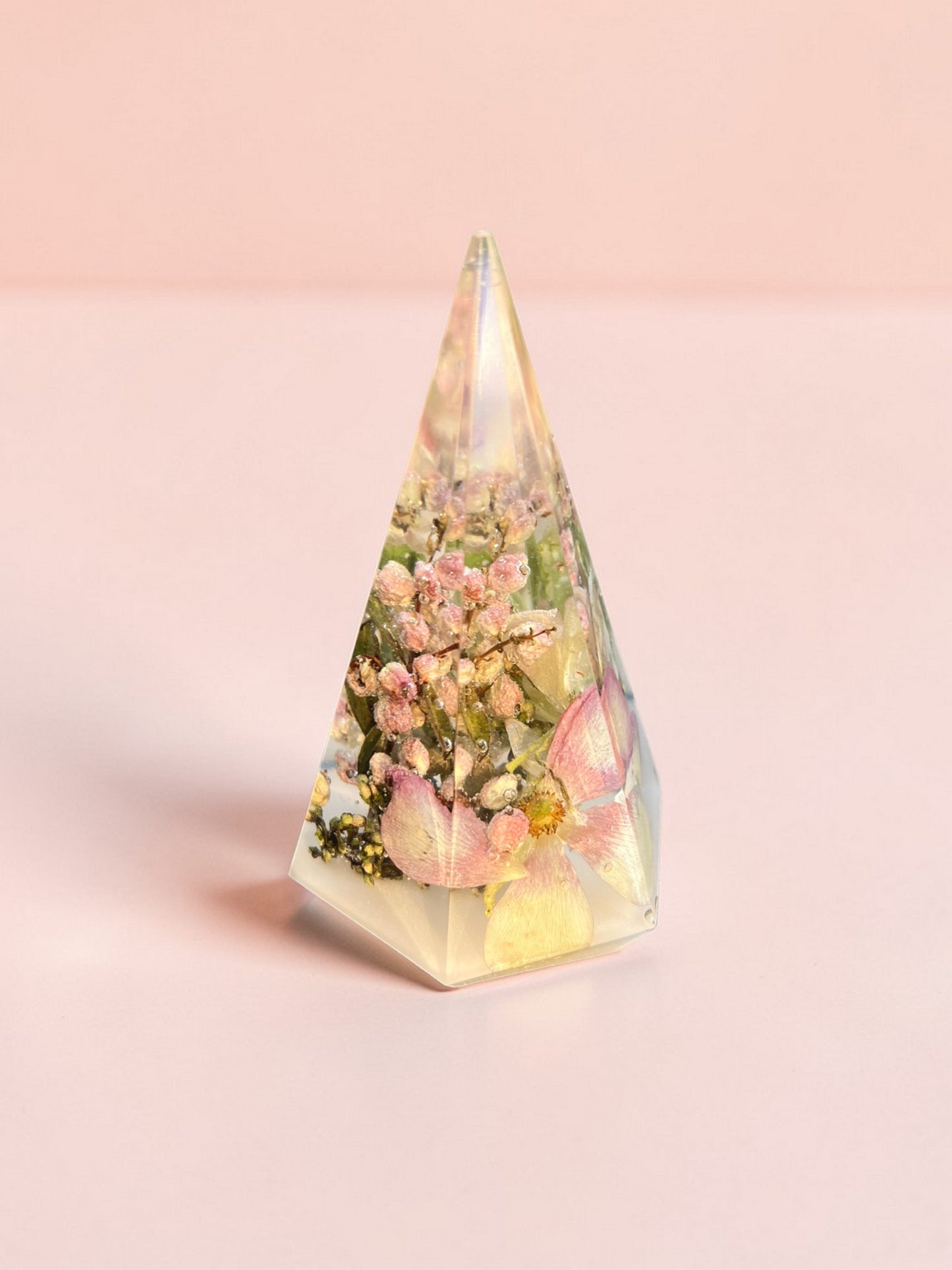 Triangular prism with floral design and light on a pink background