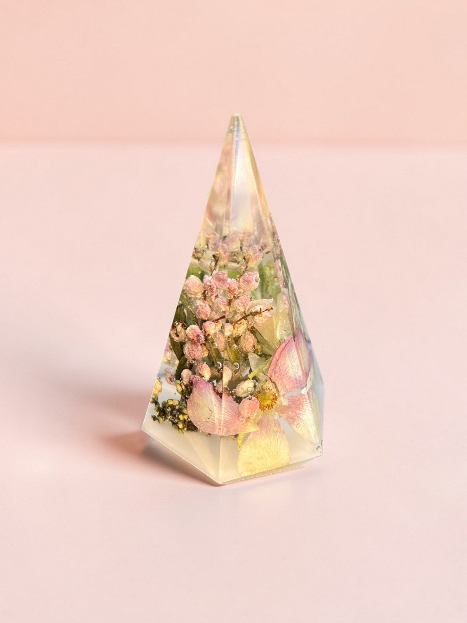 Triangular prism with floral design and light on a pink background