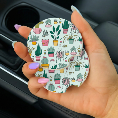 Hand holding a round car coaster with plant pattern inside a vehicle.