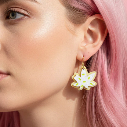 Close-up of a woman wearing a pot cookie earring with a pink background