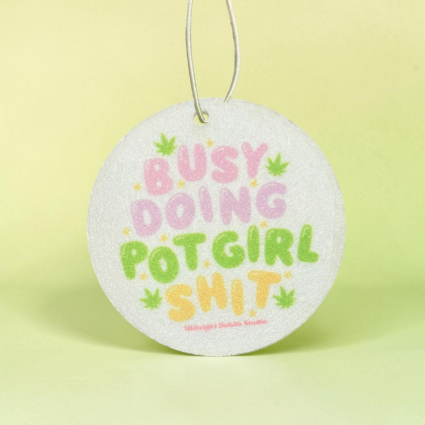 Round air freshener with colorful text on a yellow background