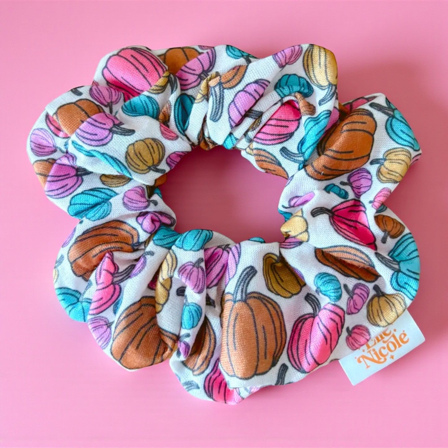 Colorful pumpkin-patterned scrunchie on a pink background