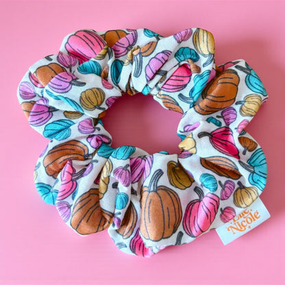 Colorful pumpkin-patterned scrunchie on a pink background