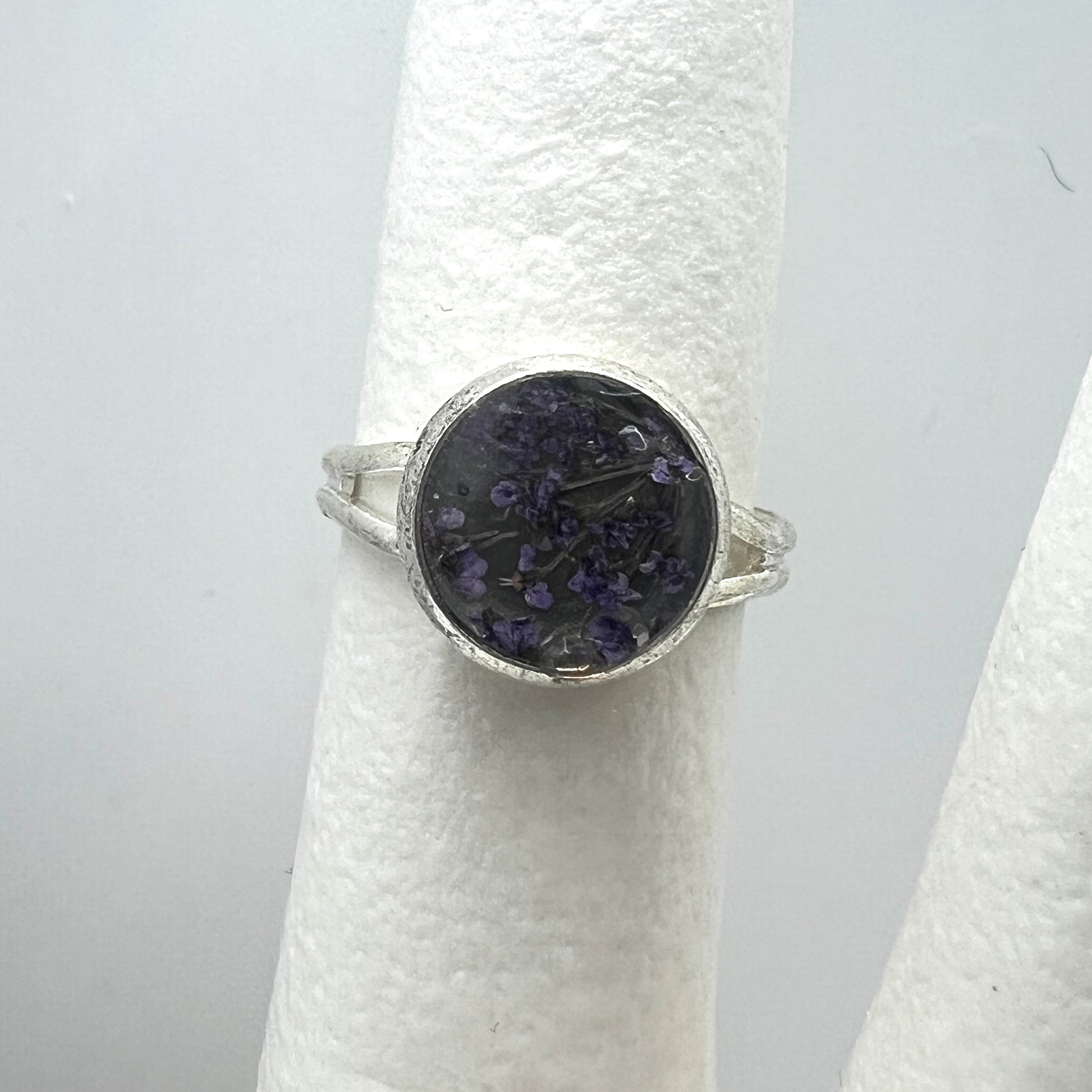Silver ring with a purple queen anne's lace real pressed flower on a white stand