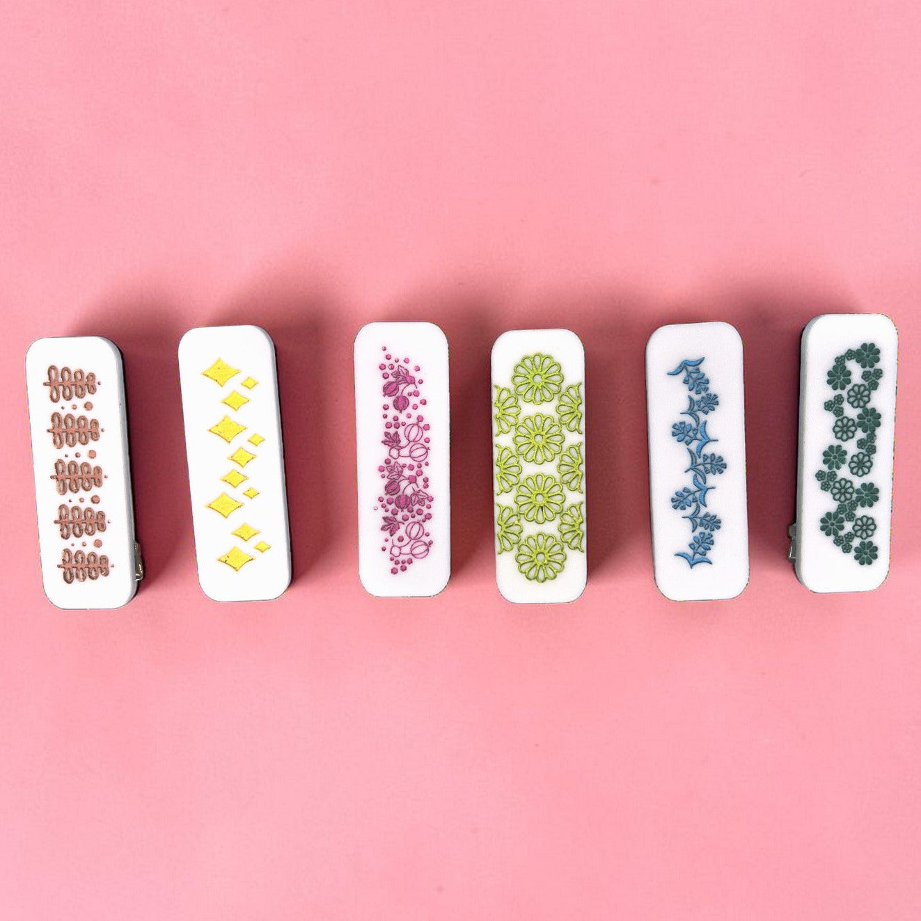 Set of six hair clips with floral patterns on a pink background