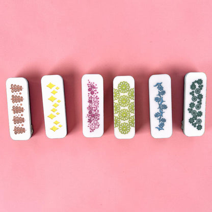 Set of six hair clips with floral patterns on a pink background