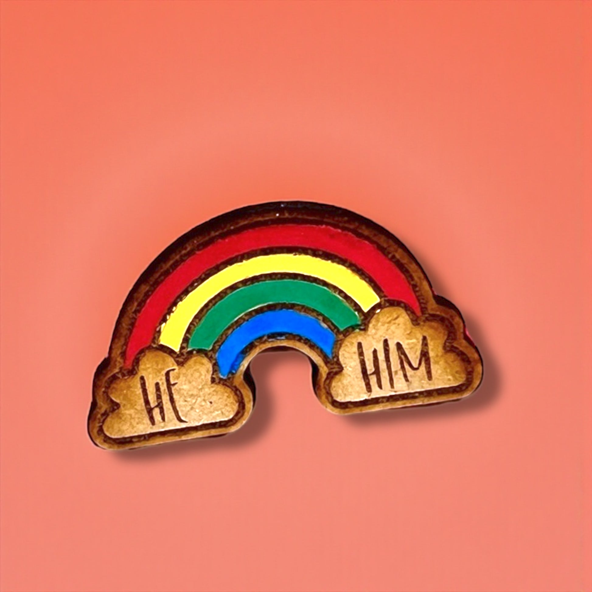 Rainbow-shaped pin with 'He' and 'Him' text on a pink background