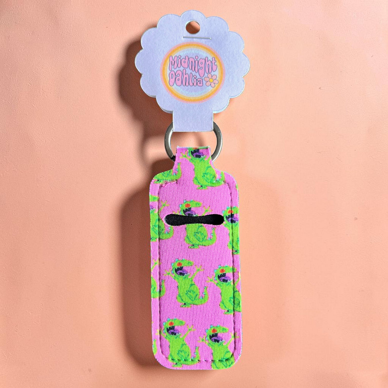 Pink key fob with green dinosaur pattern on a peach background