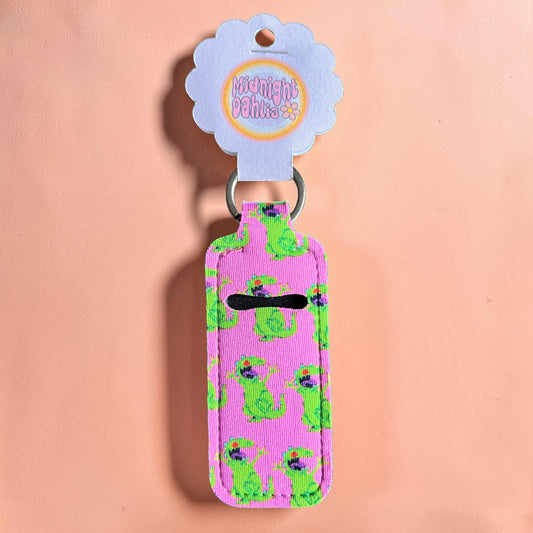 Pink key fob with green dinosaur pattern on a peach background