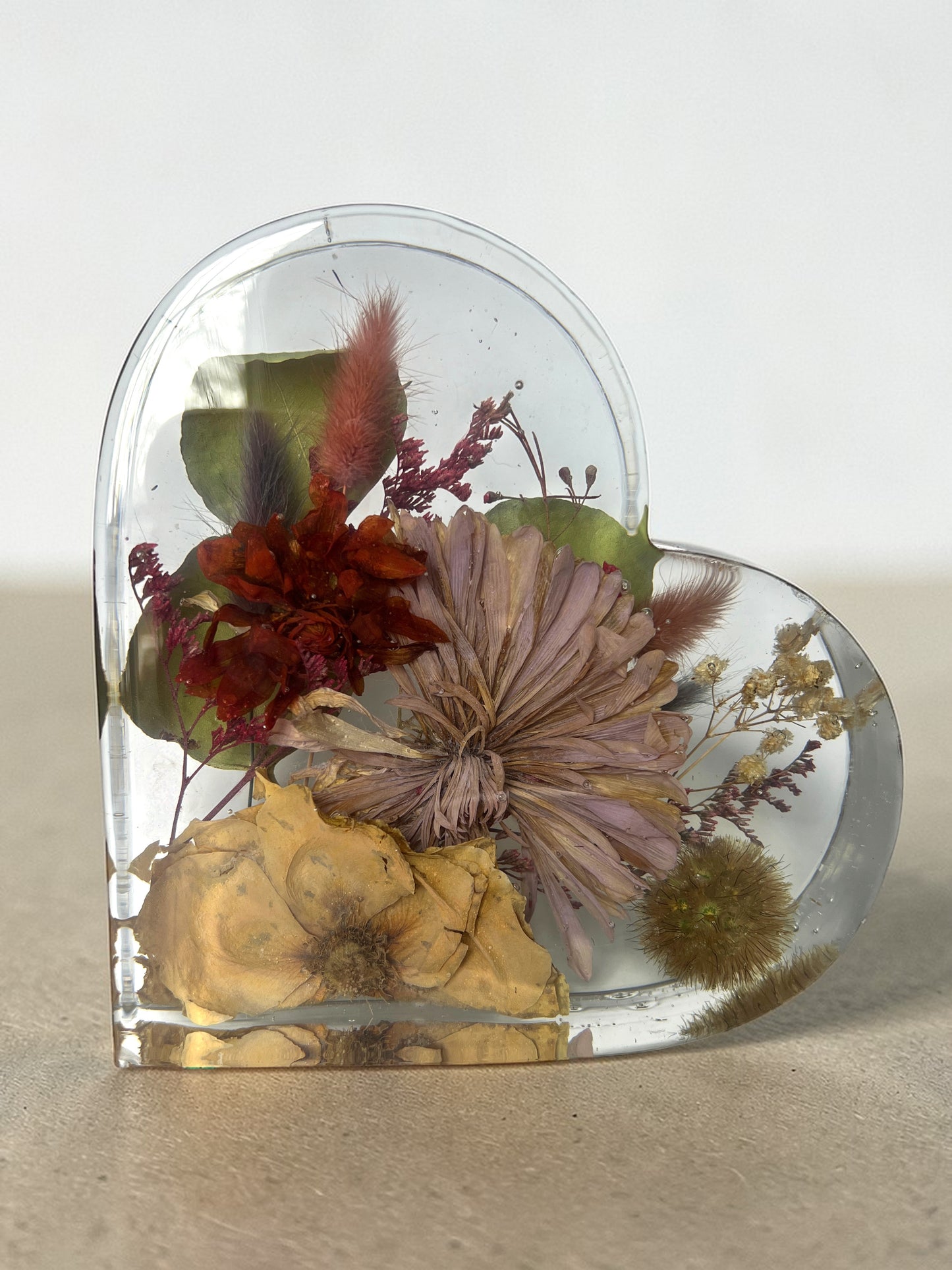Heart-shaped clear resin with preserved flowers on a neutral background