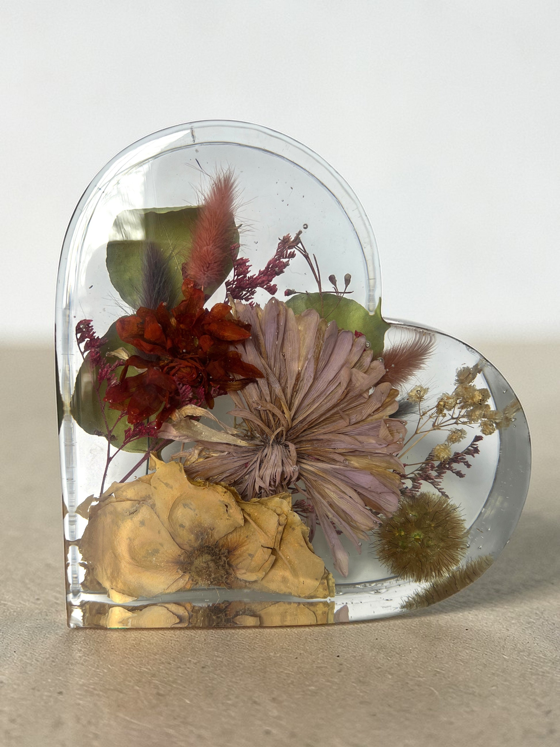 Heart-shaped clear resin with preserved flowers on a neutral background