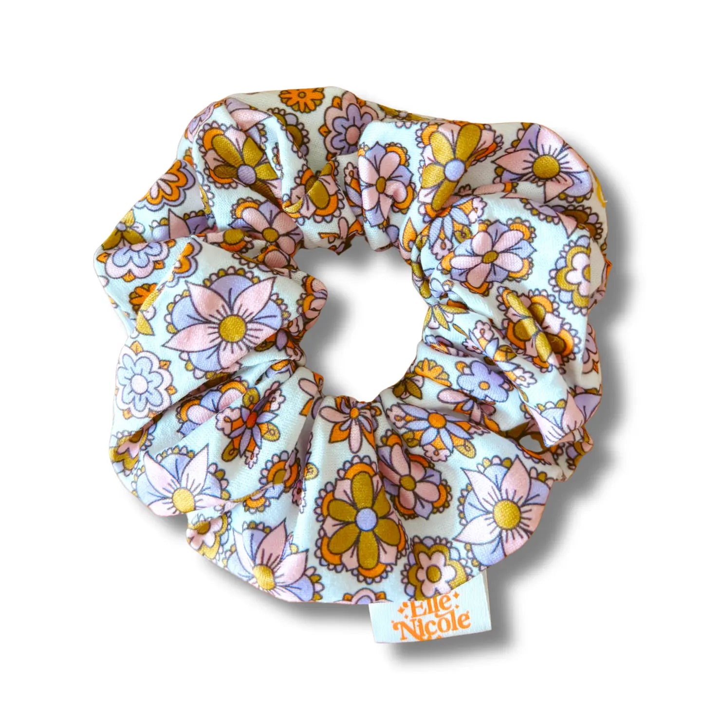 Floral patterned scrunchie with a brand label on a white background