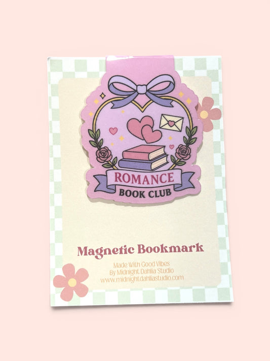 A cute pink and purple 'Romance Book Club' magnetic bookmark card, featuring a whimsical illustration of a book, hearts, and roses, set against a soft pastel pink background.