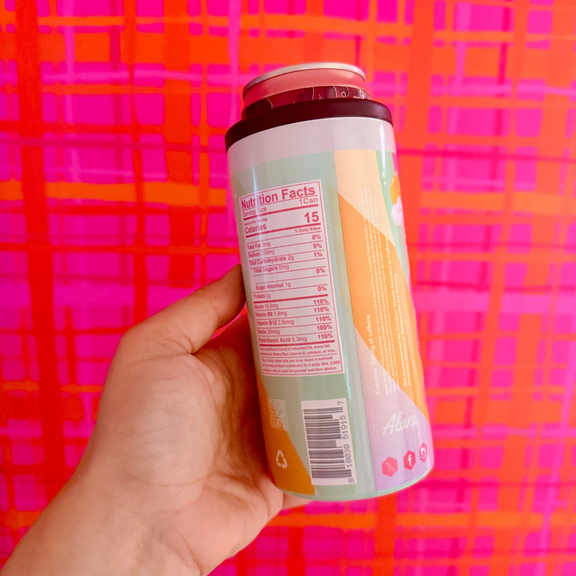 Hand holding a can with a colorful patterned background