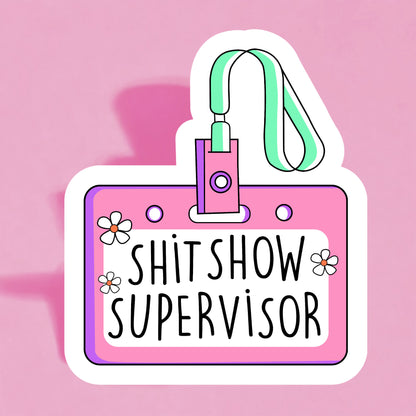 A colorful sticker with a name tag that reads 'SHIT SHOW SUPERVISOR' on a pink background, adorned with illustrations of flowers and a lanyard.