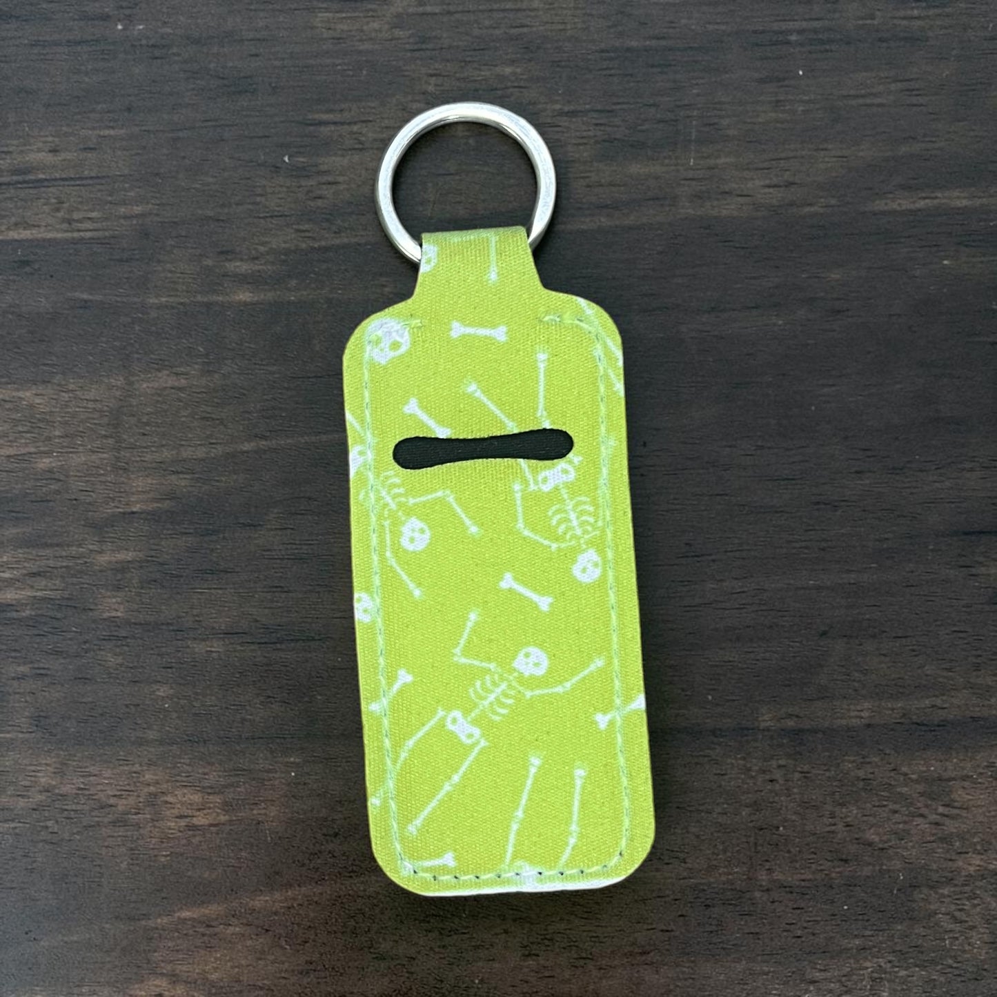 Green keychain with white patterns on a dark wooden surface