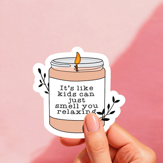 A sticker with an illustration of a candle jar and a lit candle, with the text 'It's like kids can just smell you relaxing' written on it.