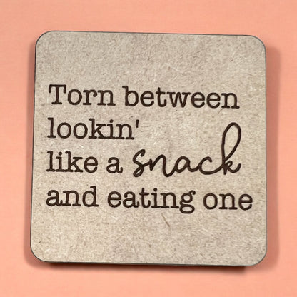 A square magnet with a humorous quote printed on it, placed against a pink background.