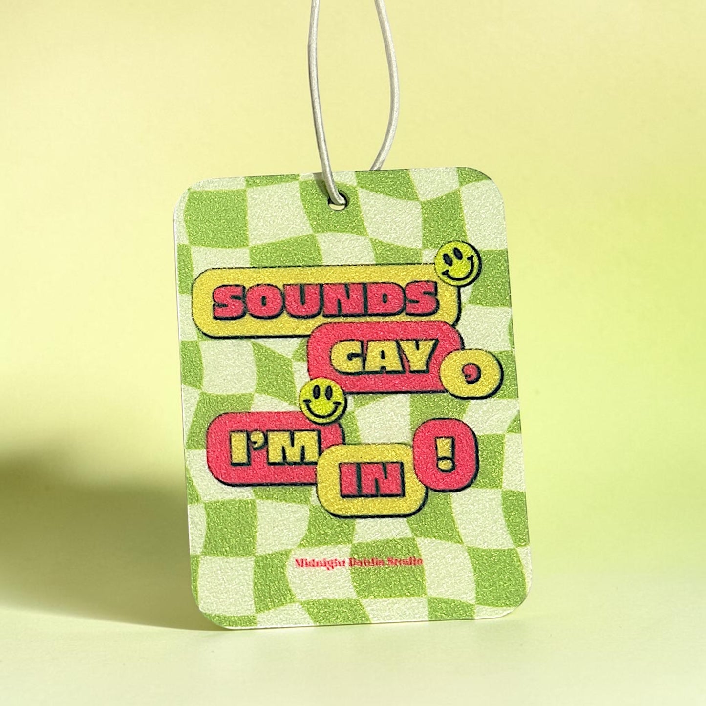 Checkered air freshener with colorful text on a yellow background