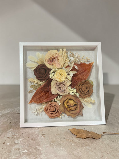 Framed arrangement of pressed flowers on a neutral background