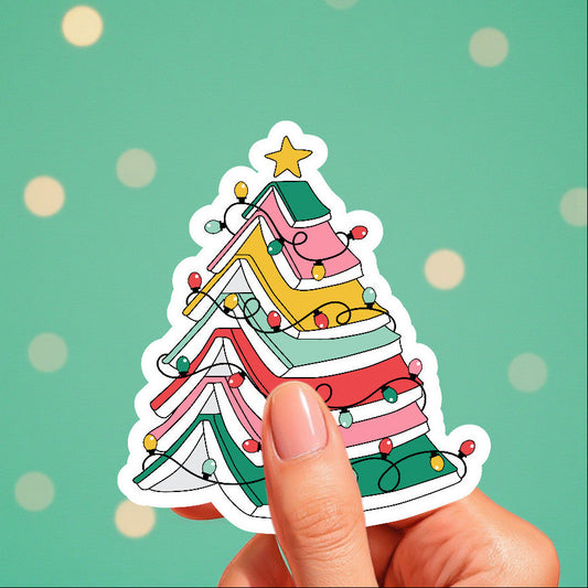 Colorful Christmas tree sticker held by a hand against a green background with polka dots.