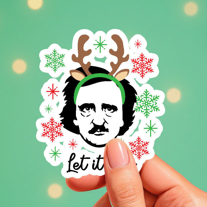Sticker with a Christmas-themed design featuring a face with reindeer antlers and snowflakes, held against a green background.