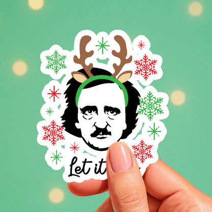 Sticker with a Christmas-themed design featuring a face with reindeer antlers and snowflakes, held against a green background.