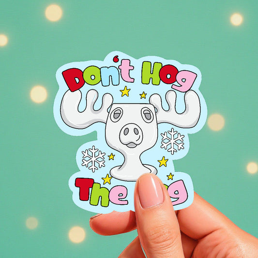 Sticker with cartoon moose and text 'Don't Hog The Hog' held by a hand against a light green background.