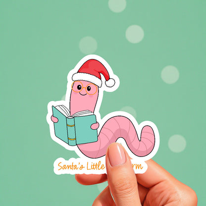Cartoon worm in a Santa hat holding a book with 'Santa's Little Bookworm' text on a green background.