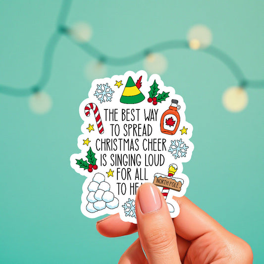Hand holding a Christmas-themed sticker with decorative elements on a teal background.