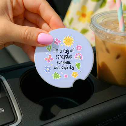 Hand holding a motivational car coaster with a drink in the background
