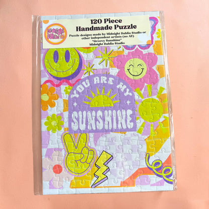 Handmade puzzle packaging with colorful designs and text on a pink background