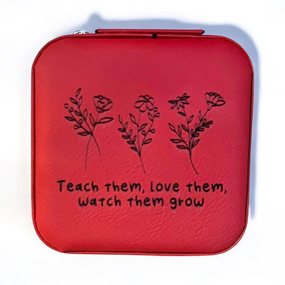 a red  jewelry box engraved in black with 'teach them love them watch them grow' with floral stems above the words