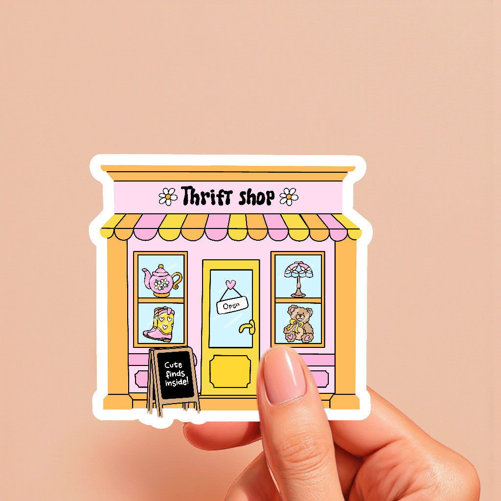 Sticker of a thrift shop with a hand holding it against a beige background