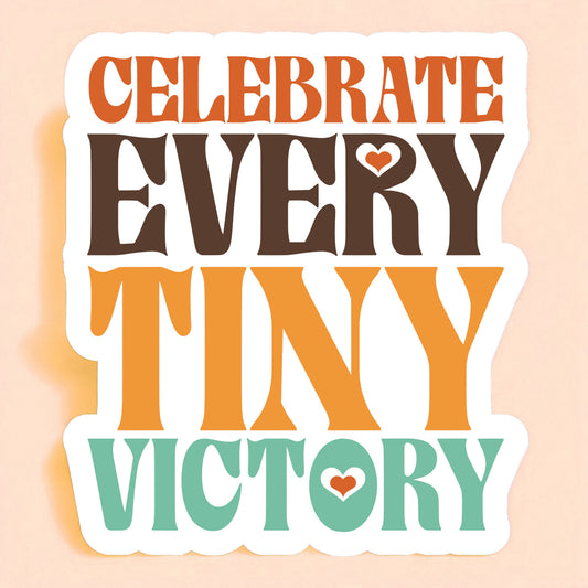 a white sticker that reads celebrate every tiny victory in orange, brown, mustard yellow, and teal