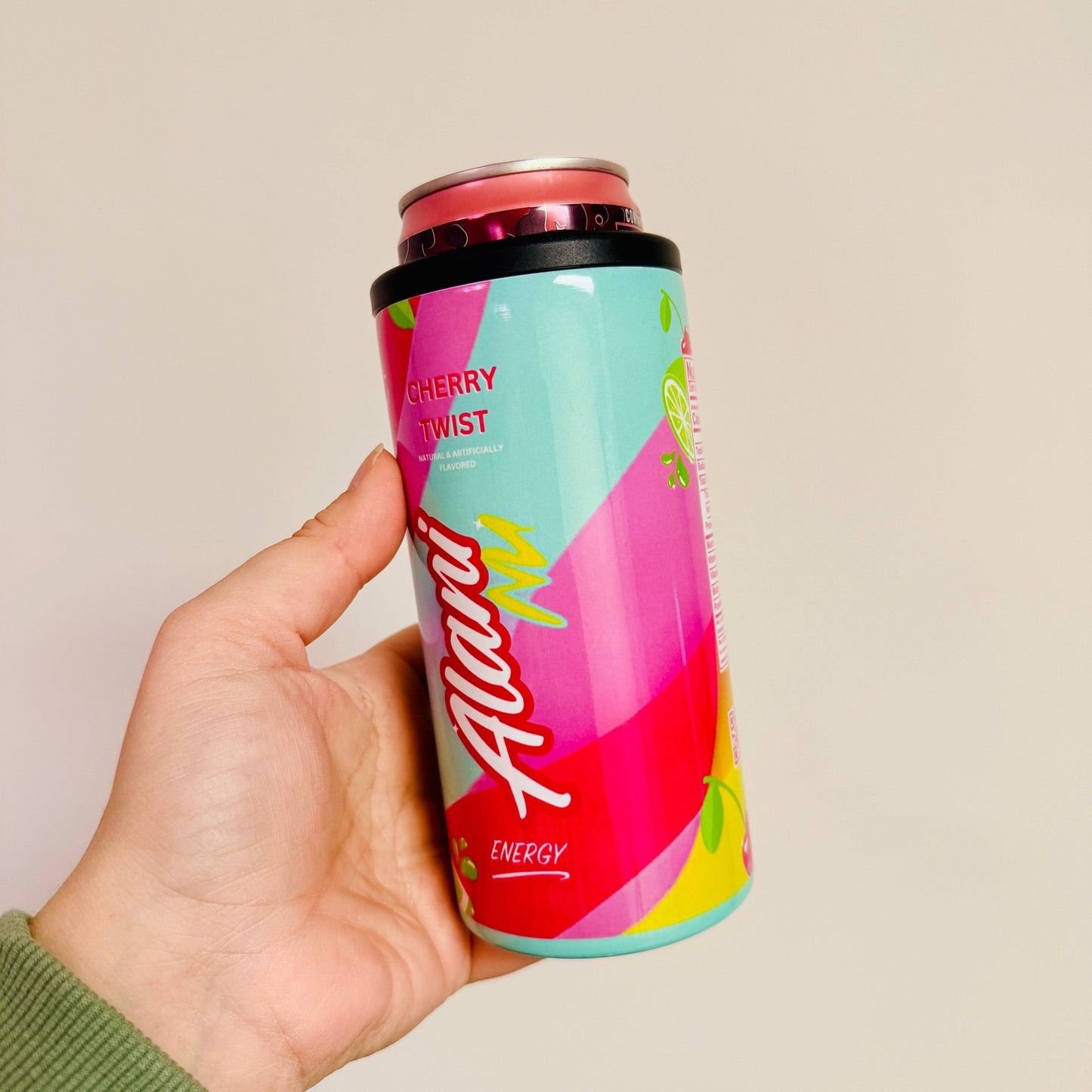 Colorful energy drink can with 'Alani' branding held by a hand against a plain background