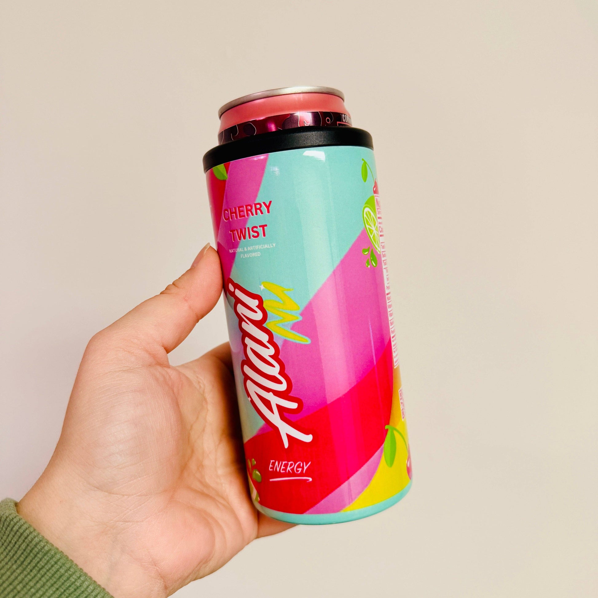 Colorful energy drink can with 'Alani' branding held by a hand against a plain background
