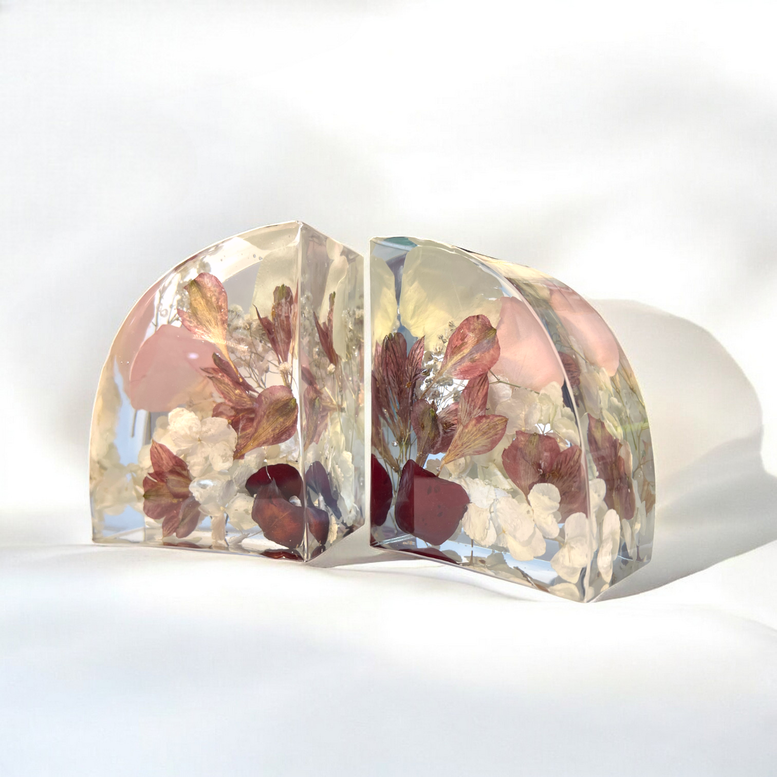 Clear resin bookends with embedded dried flowers on a white background