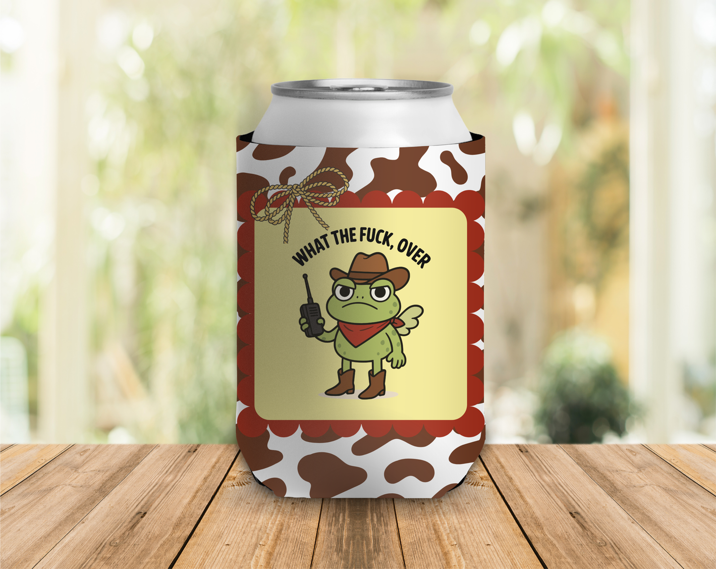 Can cooler with a cartoon frog cowboy design and text on a wooden surface.